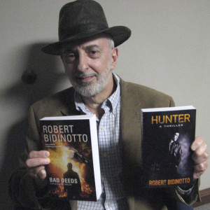 The Vigilante Author poses with his two thrillers (photo by Theresa Winslow, The Capital)
